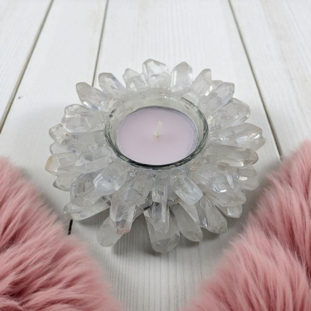 Clear quartz Crystal candle holder with a lit candle on a white wooden surface with pink fur accents.