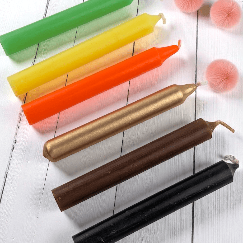 Set of colorful candles on a white wooden surface with decorative items. abundance candle set available at zen collection crystal shop in Barrie