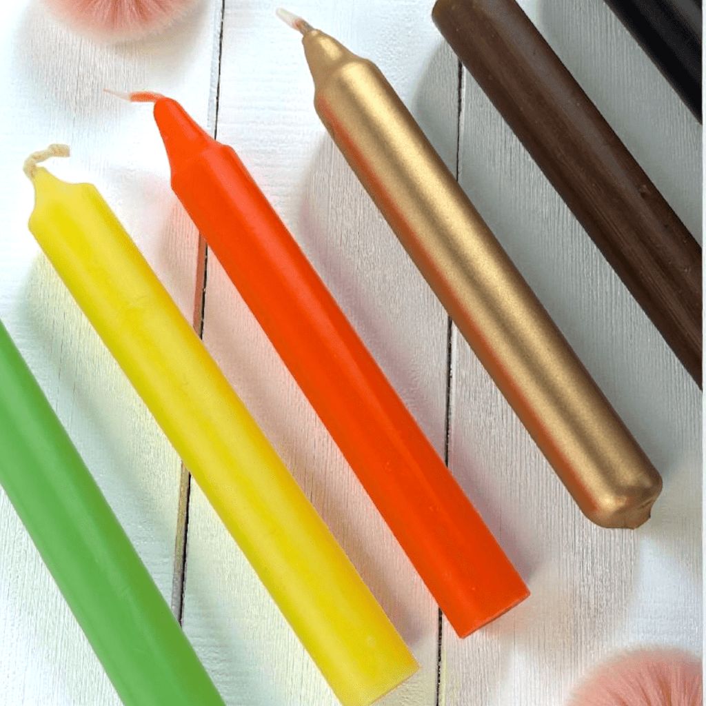 Four colorful candles (green, yellow, orange, brown) on a white wooden surface. abundance candle set available at zen collection crystal stores in barrie