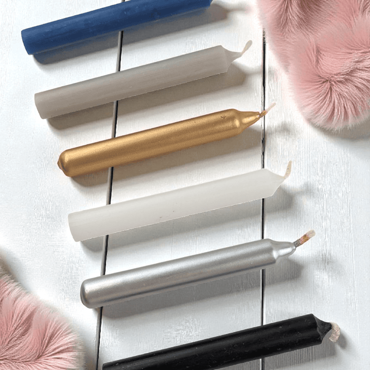 Set of metallic spell candles on a white wooden surface with pink fluffy objects. Shop in-store or online at zen collection crystal shop near me 