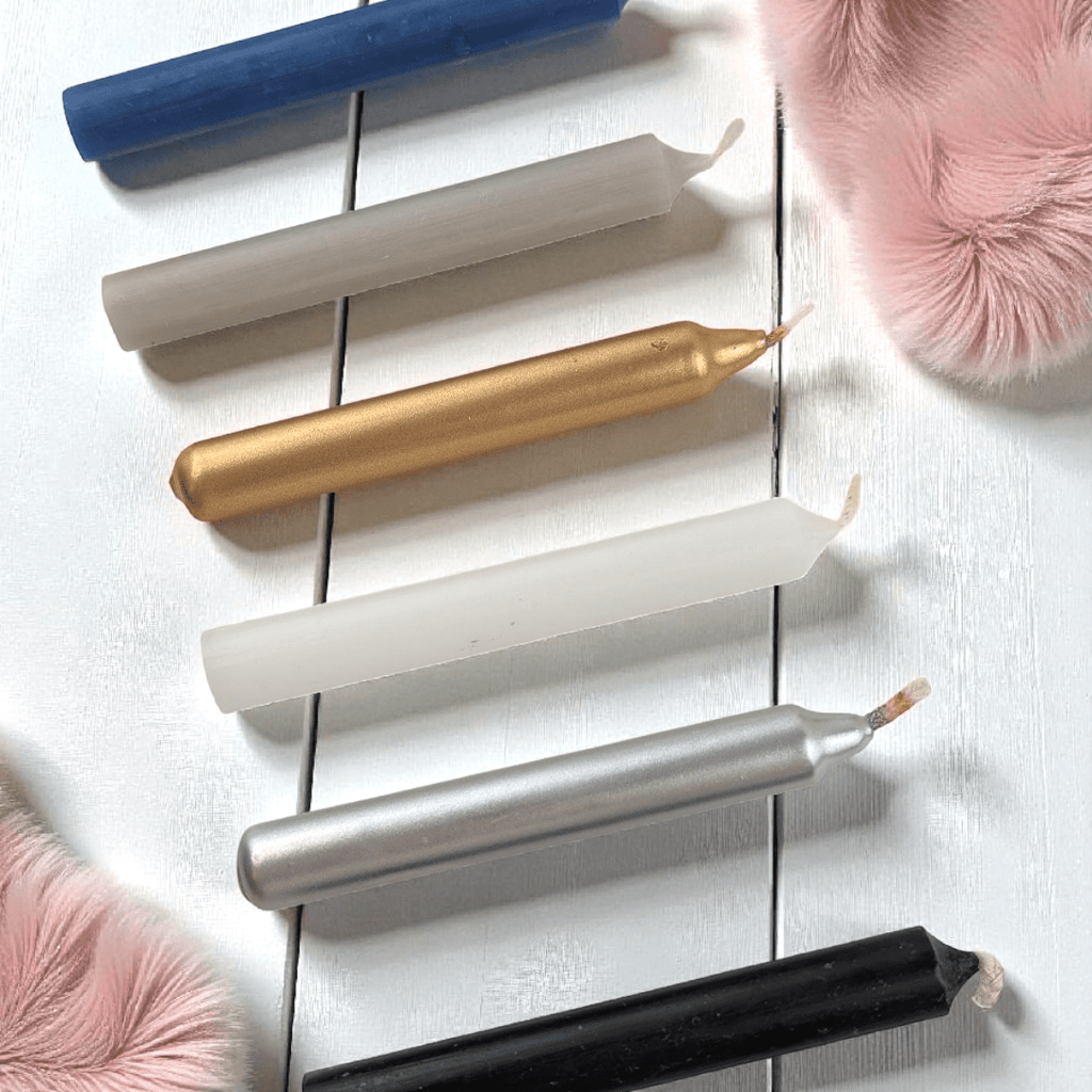 Set of metallic spell candles on a white wooden surface with pink fluffy objects. Shop in-store or online at zen collection crystal shop near me 