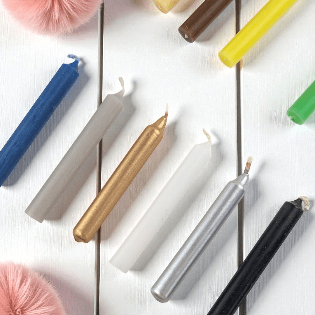 Colorful spell candles on a white surface with decorative items. shop n-store or online at zen collection crystal shop near me