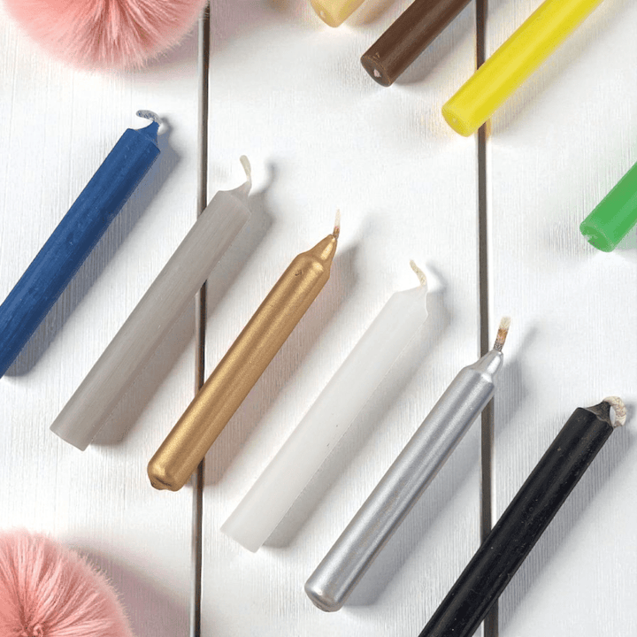 Colorful spell candles on a white surface with decorative items. shop n-store or online at zen collection crystal shop near me
