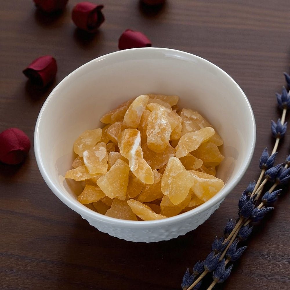 Sacral Chakra Crystals - White bowl filled with Orange Calcite Crystal pieces on a wooden surface with dried flowers. Available at Zen Collection crystal stores barrie