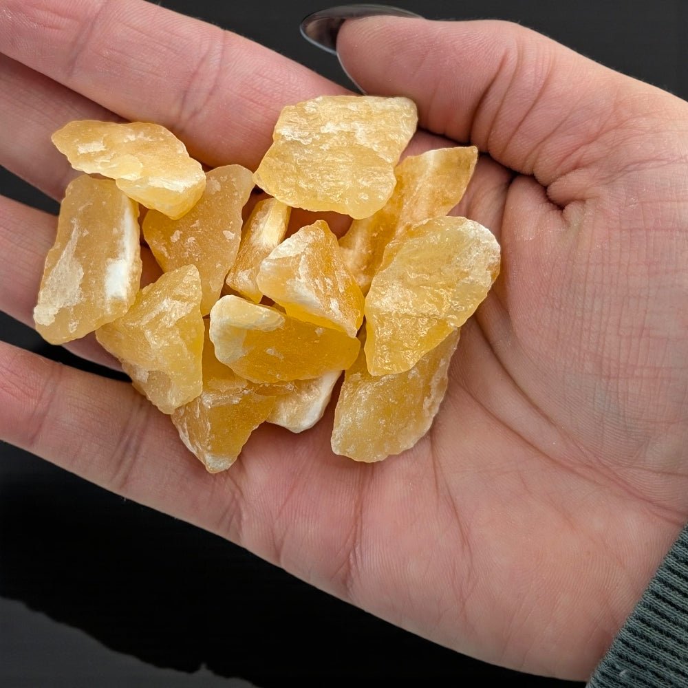 Sacral Chakra Crystals - Hand holding raw orange calcite stones against a dark background available at zen collection crystal stores barrie
