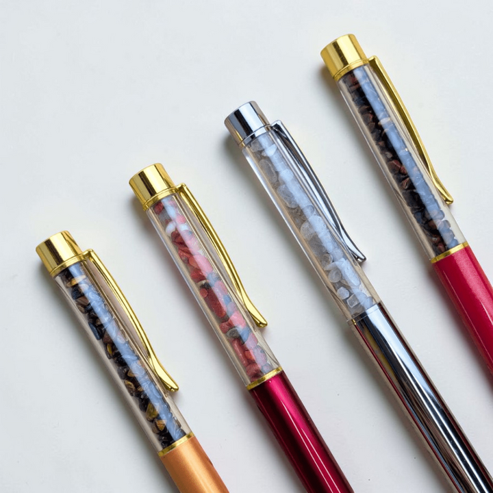 Black ink Crystal Pens with gold accents on a wooden background