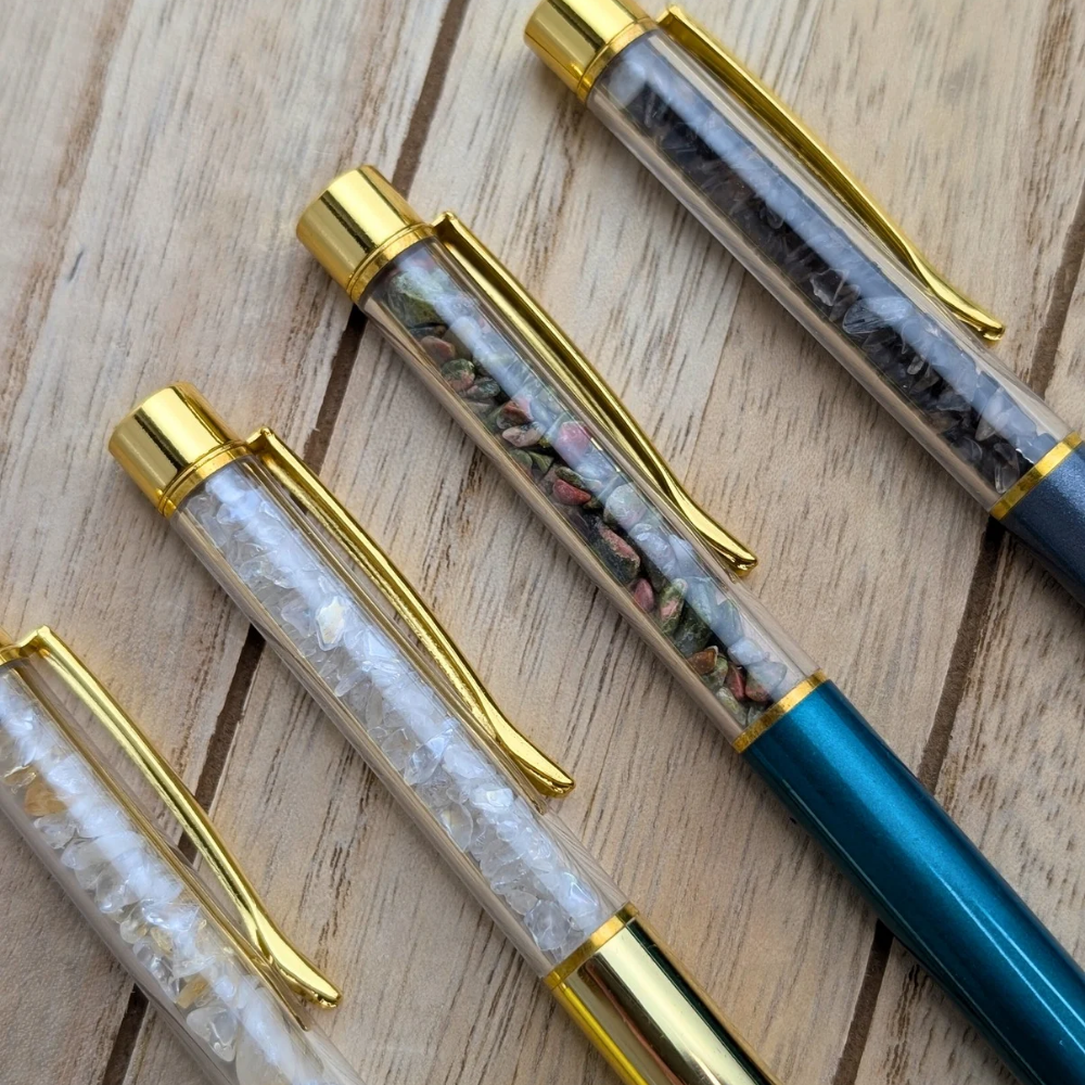 Black ink Crystal Pens with gold accents on a wooden background