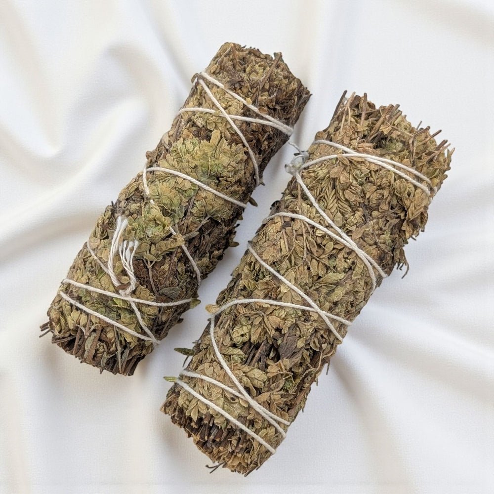 Two bundles of pure oregano bundle for cleansing and protection tied together on a white fabric background available at barrie crystal store