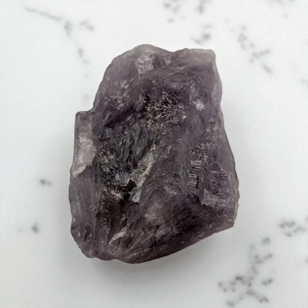 Raw amethyst crystal on a marble surface