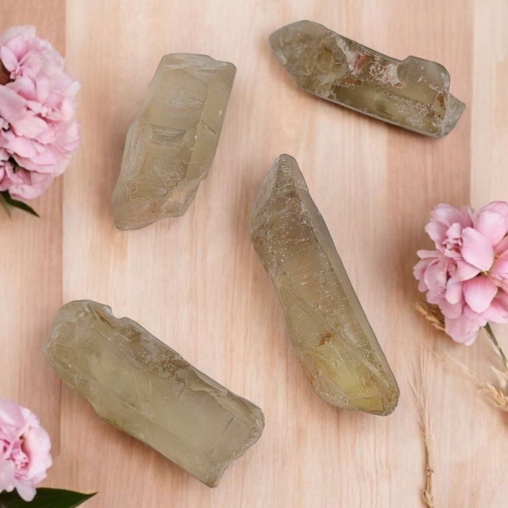Raw natural citrine crystal stones on a wooden surface with pink flowers