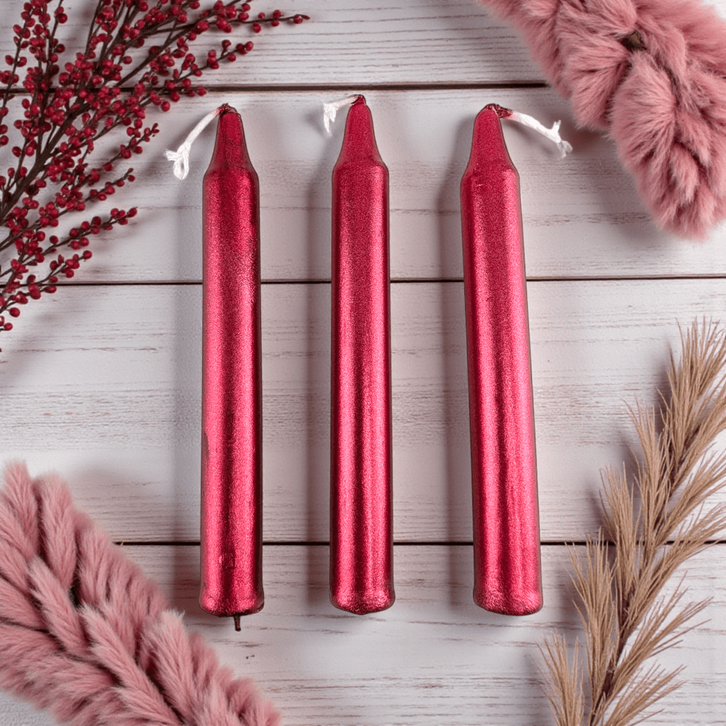 Three red spell candles on a white wooden surface with pink and gold decorative elements. Shop In-Store now or online 24/7 at Zen Collection  Crystal Stores Barrie