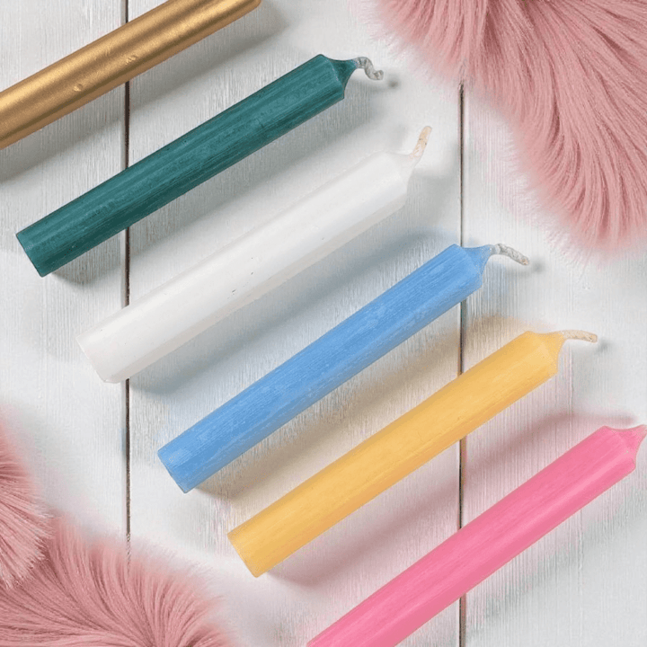 Colorful spell  candles on a wooden surface with pink feathers available at zen collection crystal store Barrie