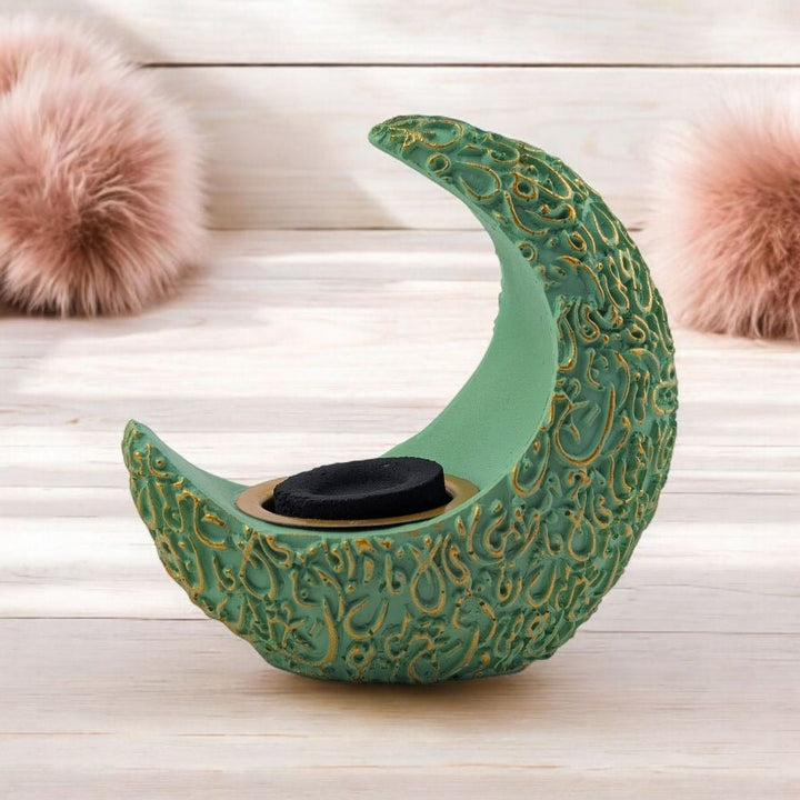 Decorative green crescent moon resin burner with gold patterns on a wooden surface