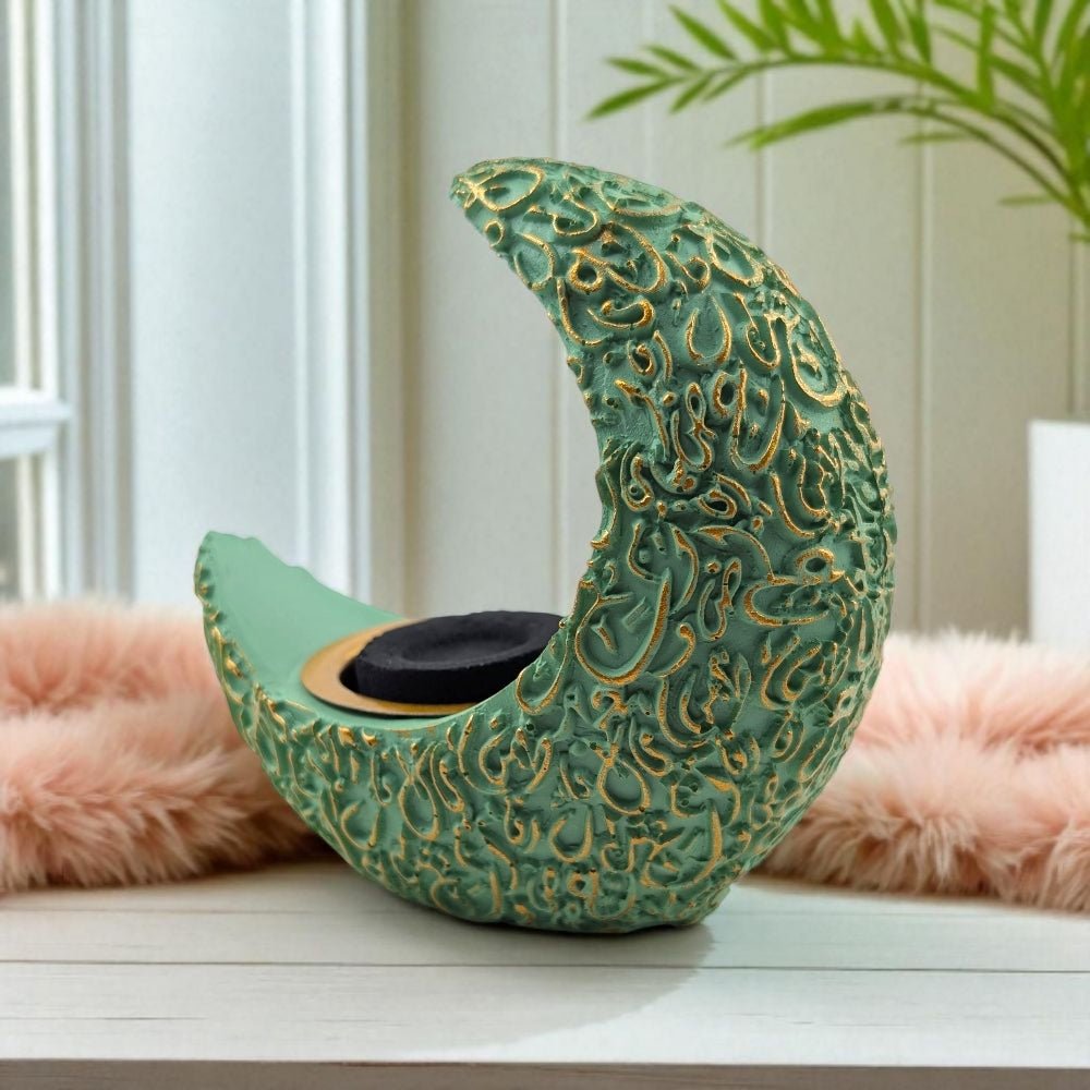Decorative green crescent moon resin burner with intricate gold patterns on a white surface.