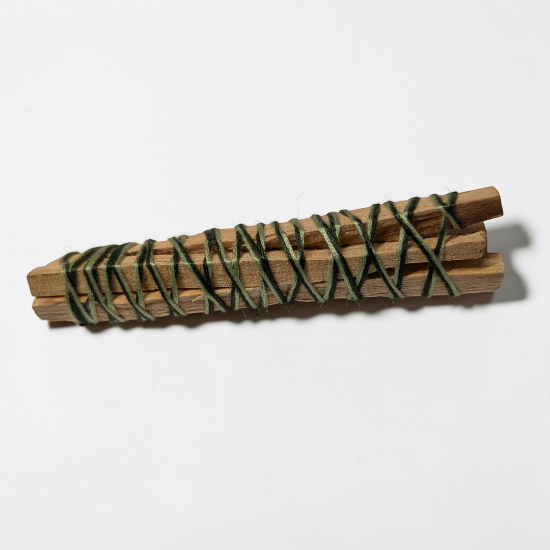 A bundle of four Palo Santo sticks tied with twine on a wooden table