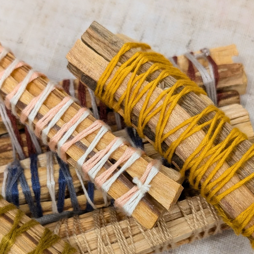 A bundle of four Palo Santo sticks tied with twine on a wooden table