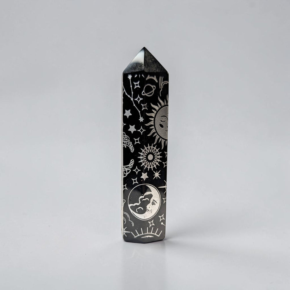 Zen Collection black obsidian crystal tower featuring intricate silver celestial engravings of suns, moons, and stars.
