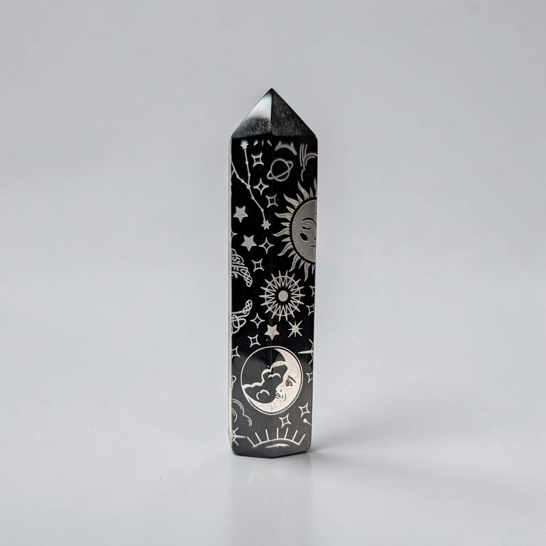 Zen Collection black obsidian crystal tower featuring intricate silver celestial engravings of suns, moons, and stars.