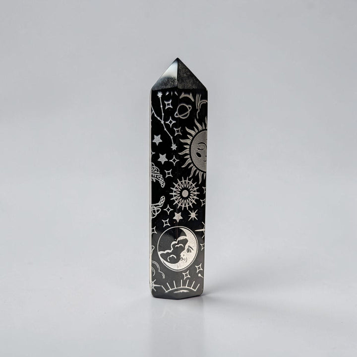 Zen Collection black obsidian crystal tower featuring intricate silver celestial engravings of suns, moons, and stars.