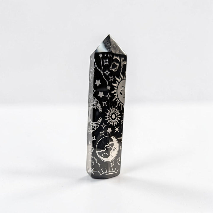 Zen Collection black obsidian crystal tower featuring intricate silver celestial engravings of suns, moons, and stars.