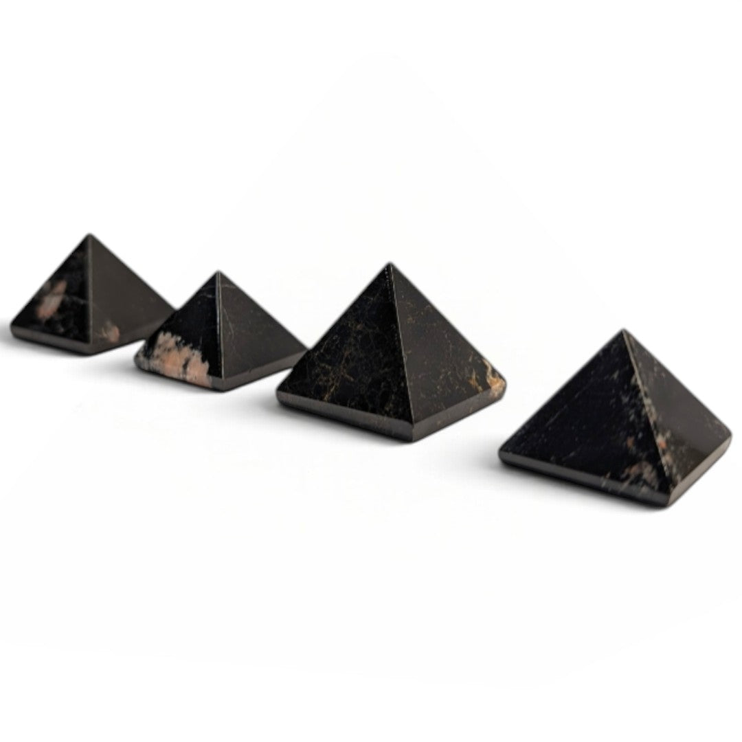Zen Collection black tourmaline crystal pyramids arranged in a row on a soft white fabric background.