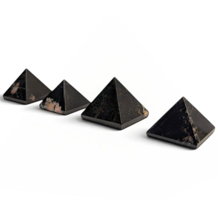 Zen Collection black tourmaline crystal pyramids arranged in a row on a soft white fabric background.