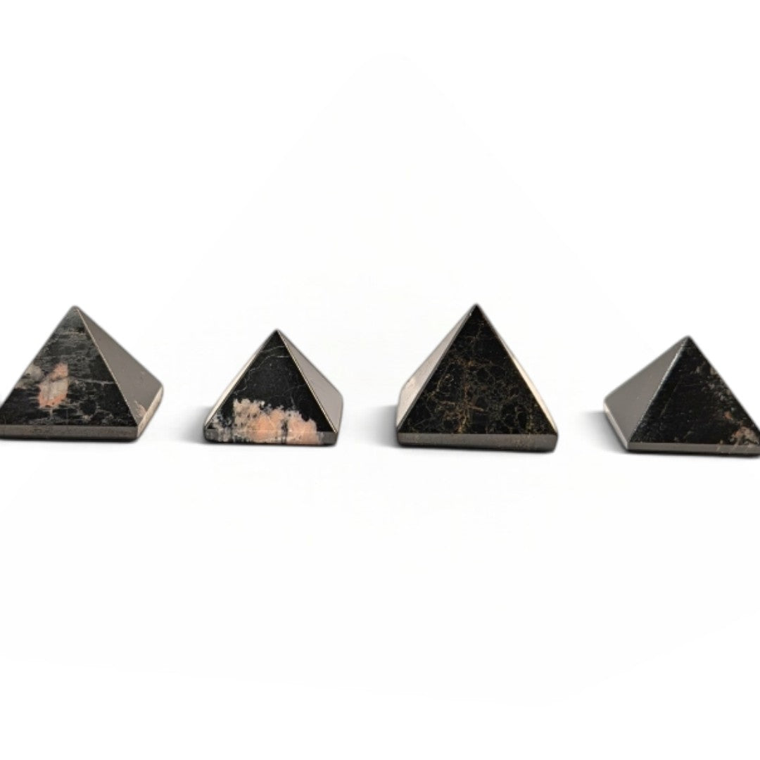 Zen Collection black tourmaline crystal pyramids arranged in a row on a soft white fabric background.