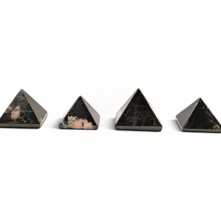 Zen Collection black tourmaline crystal pyramids arranged in a row on a soft white fabric background.