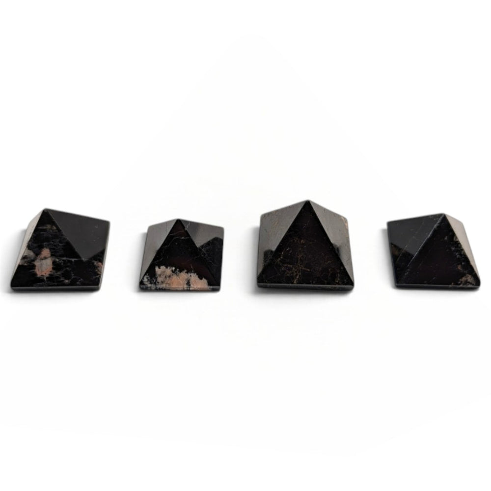 Zen Collection black tourmaline crystal pyramids arranged in a row on a soft white fabric background.
