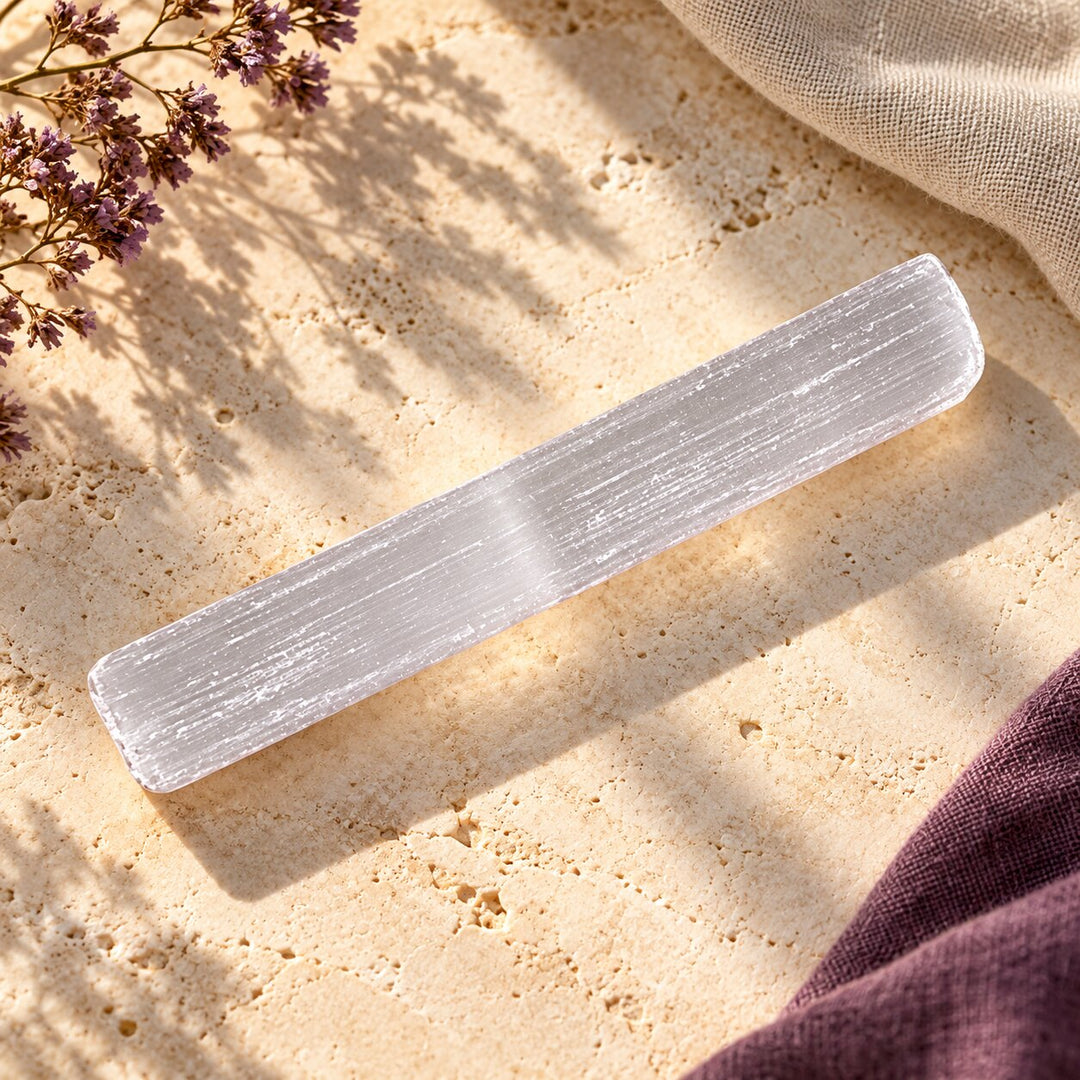 Single selenite stick with natural white fibrous striations styled on warm limestone.