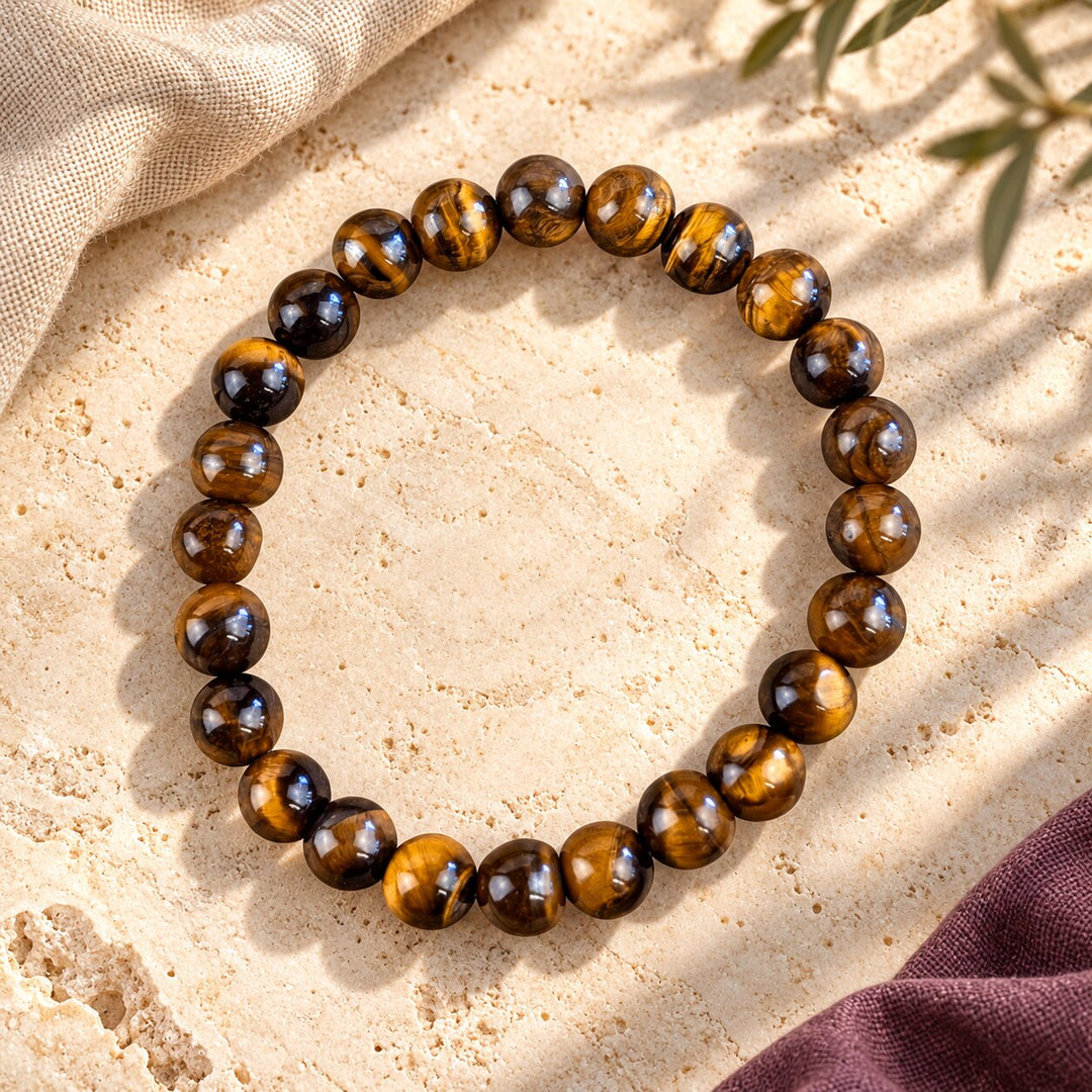 Tiger’s eye bracelet with polished brown and gold chatoyant beads styled on warm limestone.